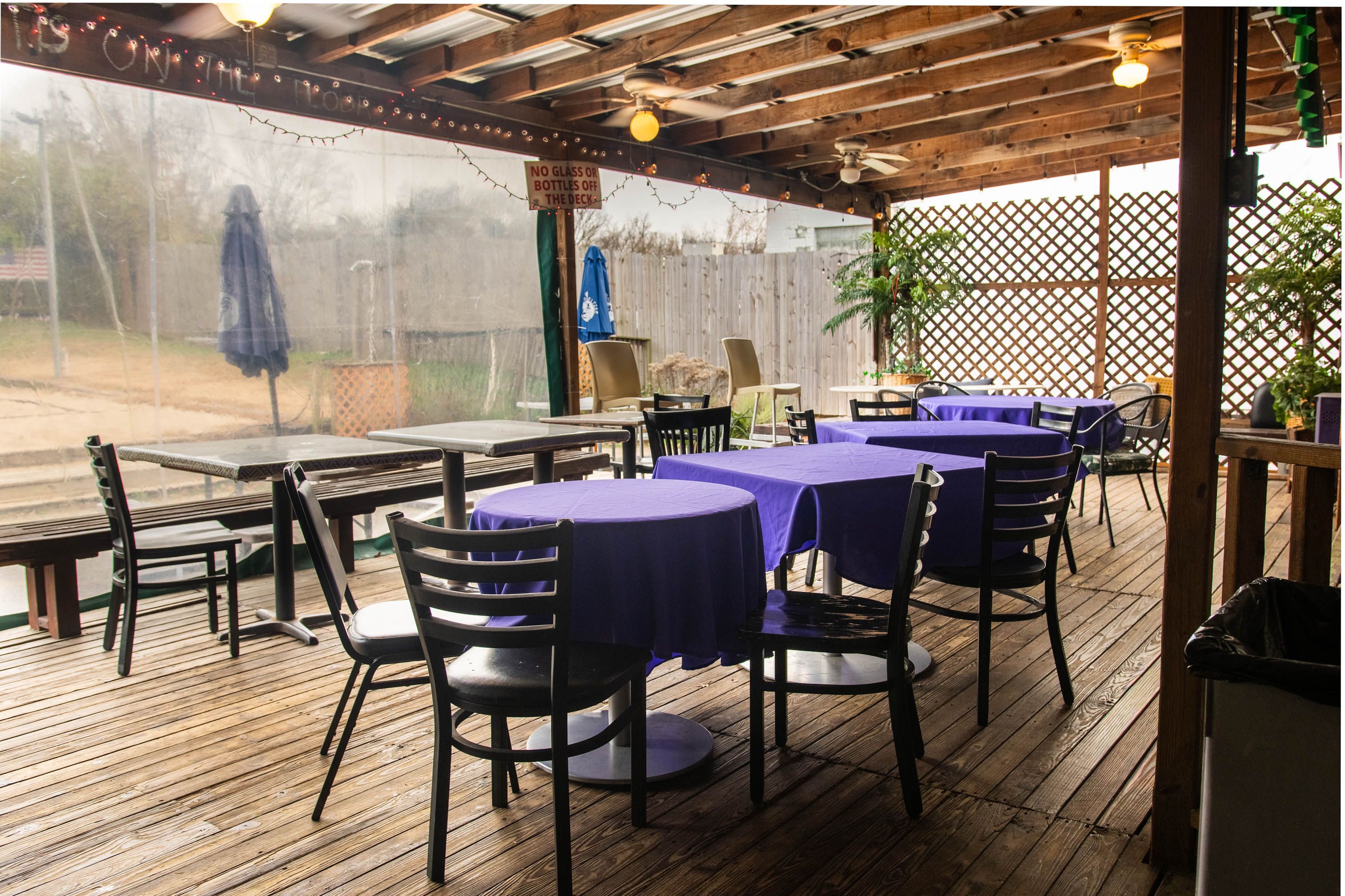 The covered deck at Bar South, tables set out, looking toward the sand court