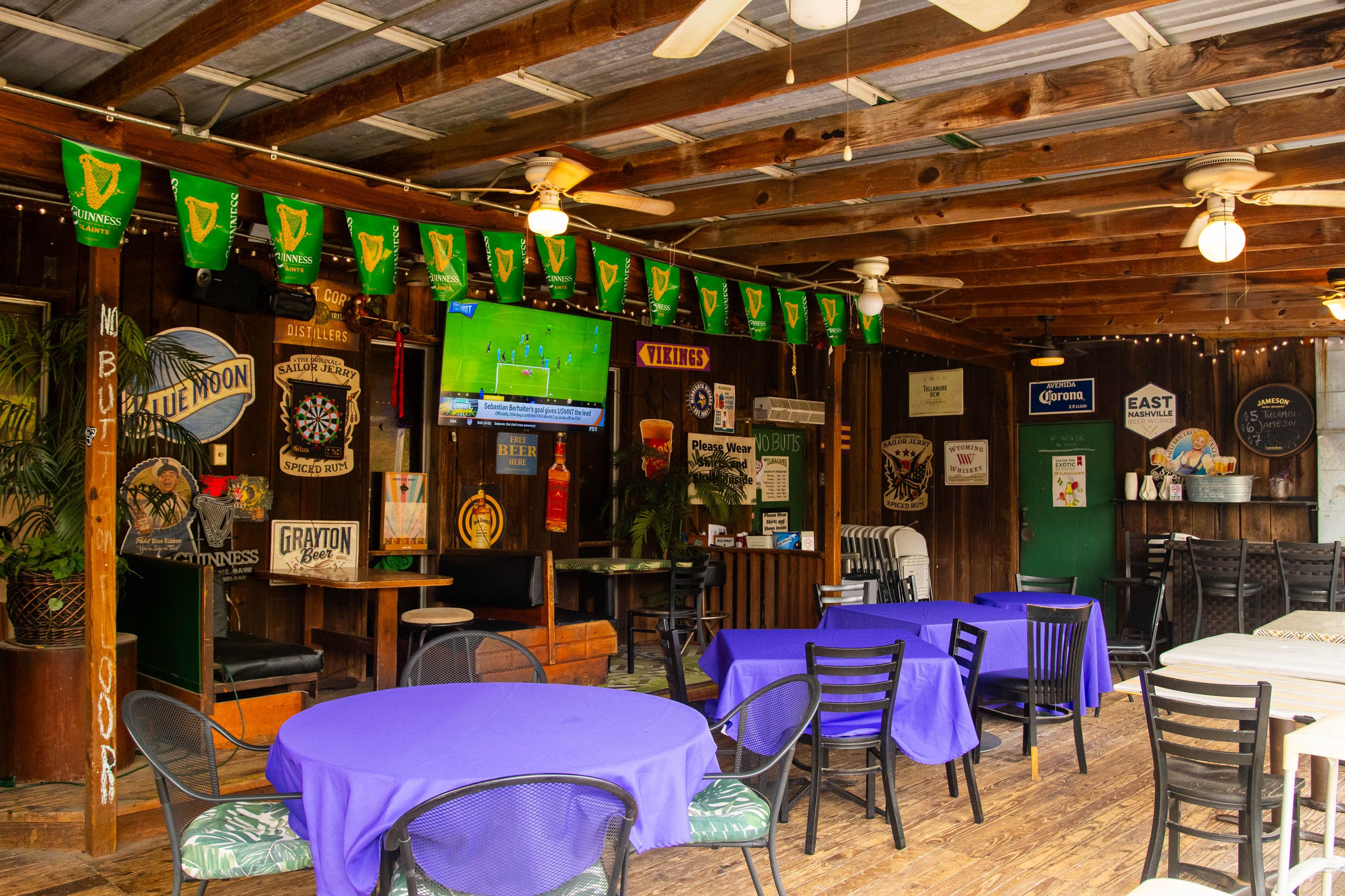 The covered patio at Bar South: TVs along the wall, pennants overhead, tables ready